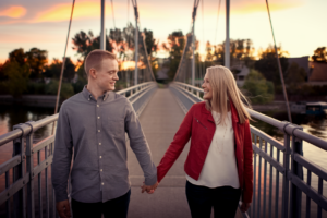 Couple holding hands on a bridge during sunset, symbolizing trust and healing.