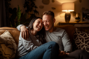 A couple laughing and enjoying a moment of friendship on a cozy couch