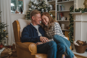 Couple laughing together in a cozy living room, symbolizing humor as a weapon against stress.