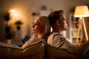 A couple sitting apart on a couch, symbolizing a lack of intimacy in a relationship.