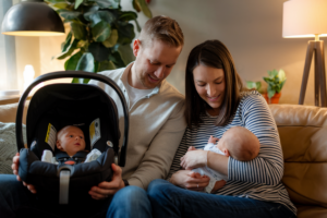 A Kodak-quality photo of a tired couple with a newborn baby, showing love and exhaustion, in a cozy home setting.